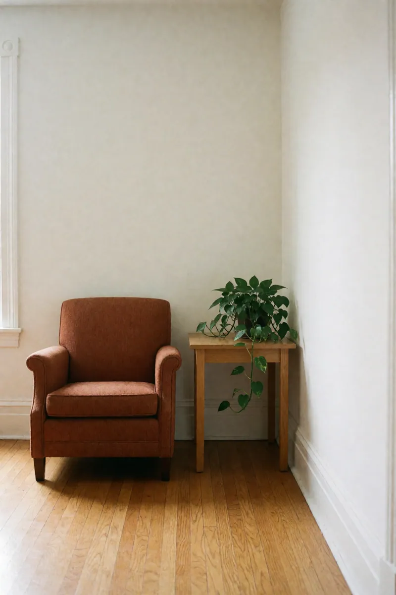 A rust upholstered armchair beside a wooden side table with a trailing pothos plant.